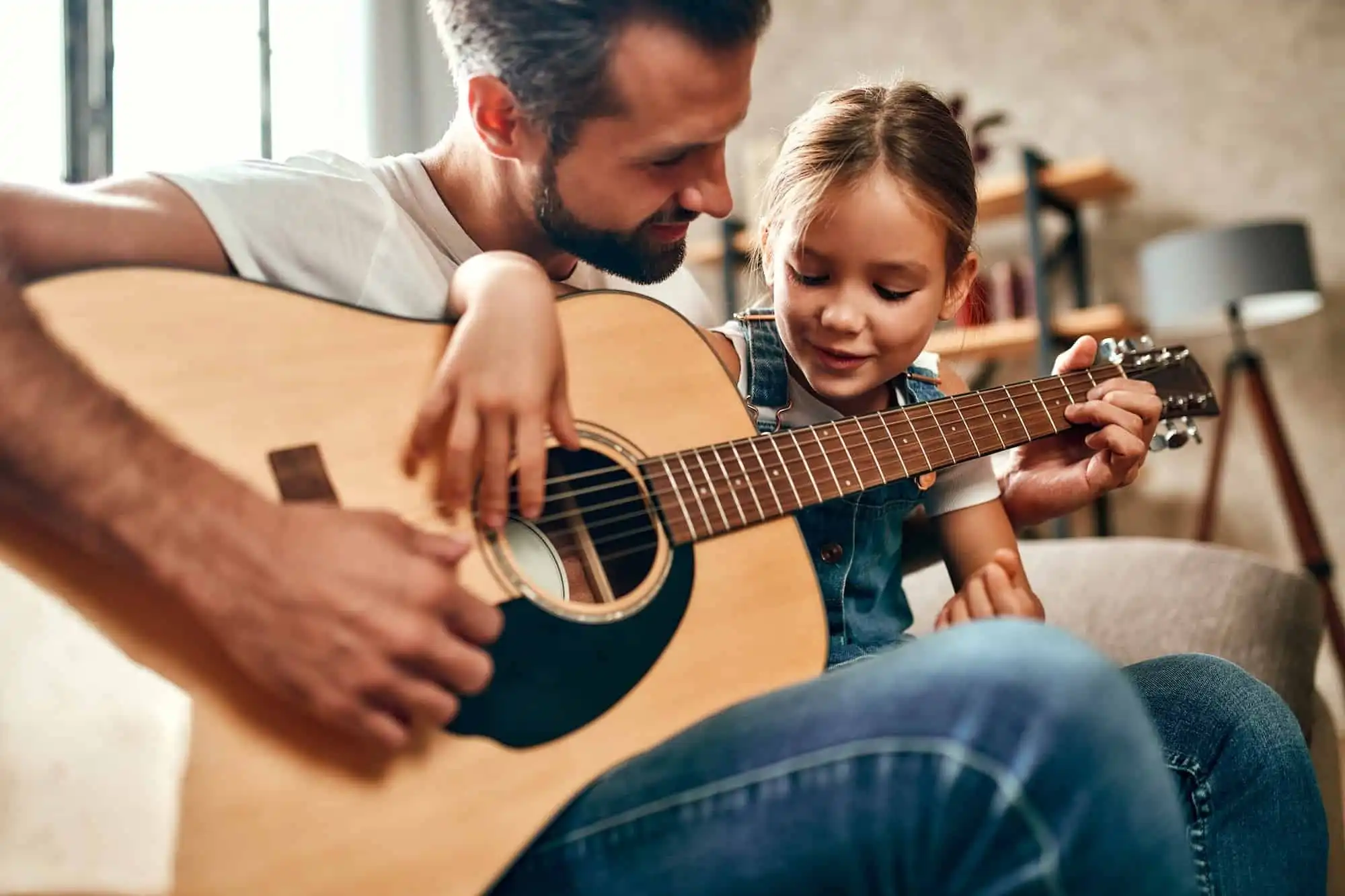 Father playing guitar with his daughter at home